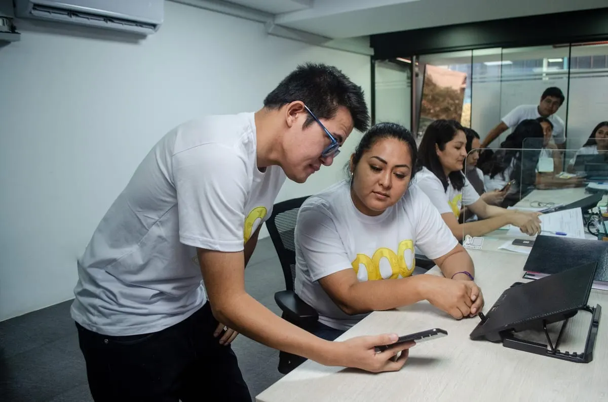 Dos integrantes del equipo de Only One Coin resolviendo una consulta